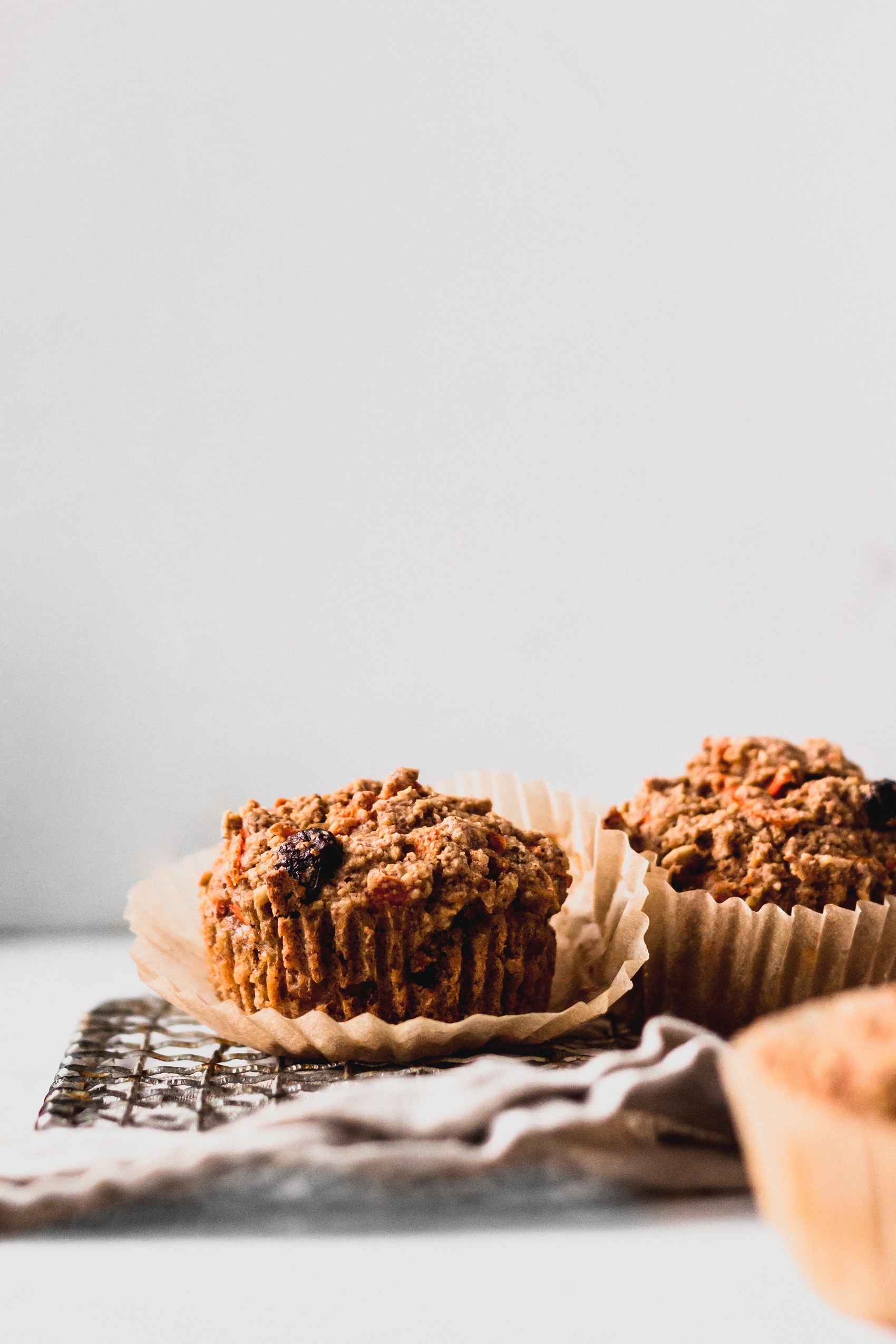 two vegan carrot cake muffins resting on a cooling rack