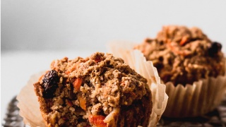 a close up shot of a carrot muffin with a bite taken from it