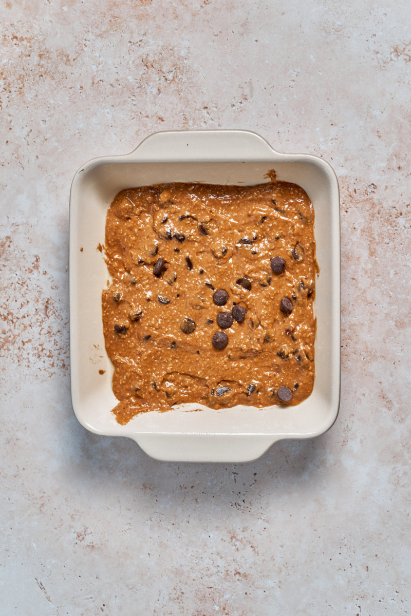 a baking dish filled with almond butter blondie batter topped with chocolate chips