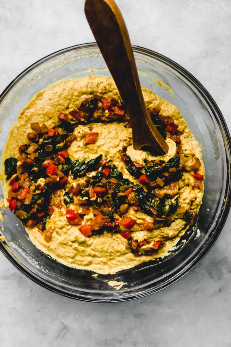 a bowl of chickpea flour pancake batter being mixed with a wooden spoon