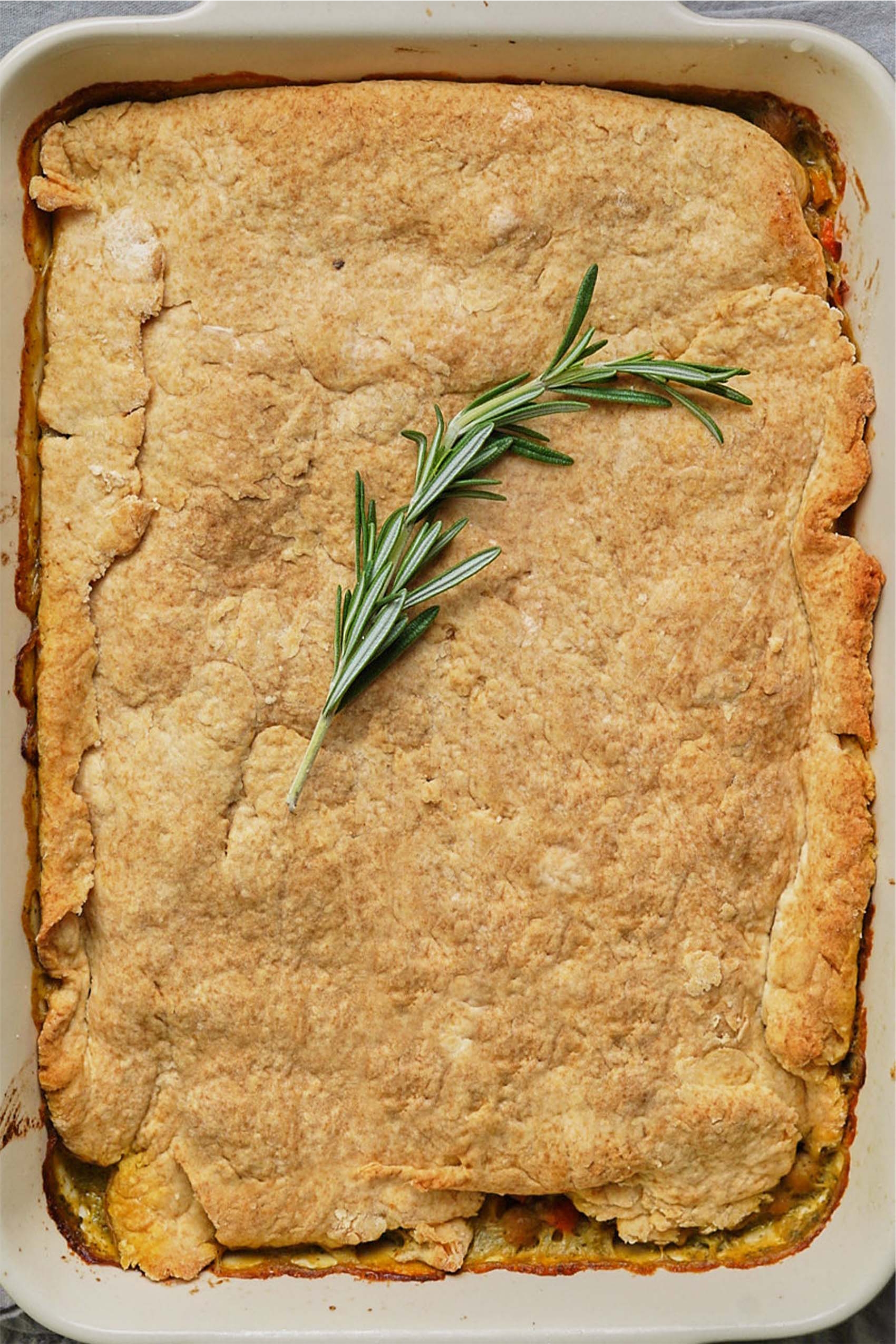 a casserole dish filled with vegan chickpea pot pie, topped with a sprig of rosemary