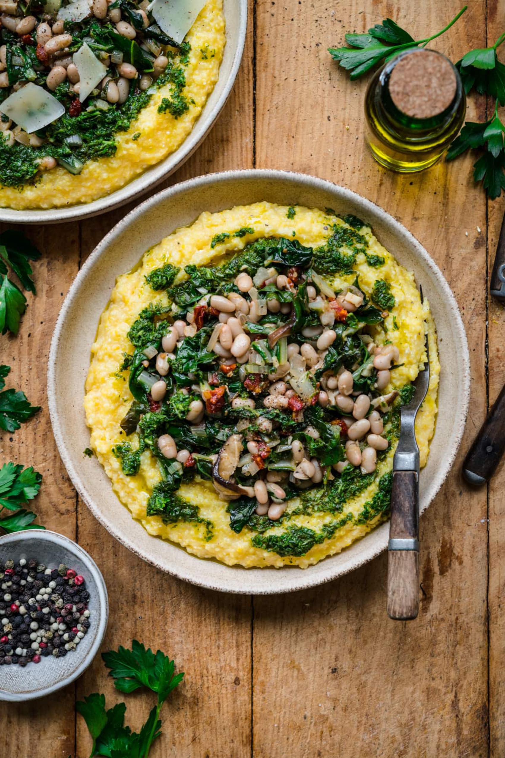 a bowl of polenta topped with white beans and veggies