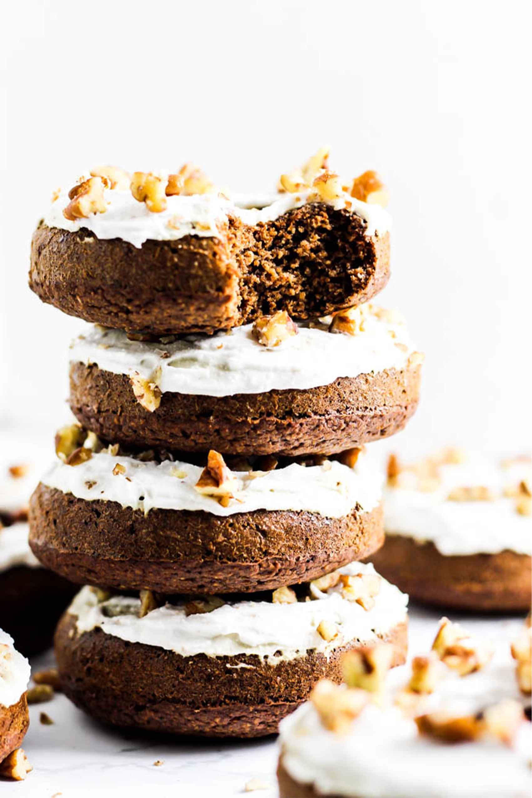 a stack of vegan gingerbread donuts topped with walnuts