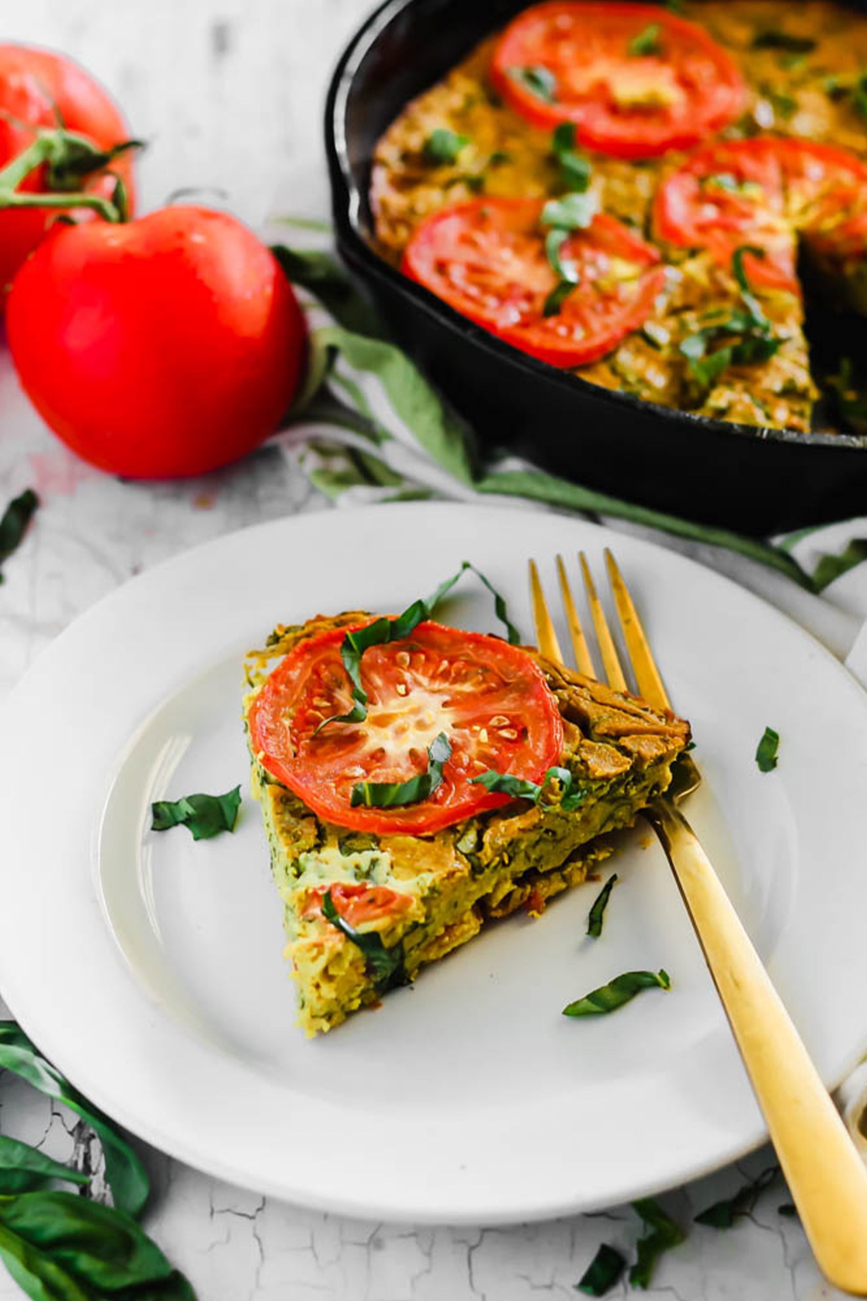 a slice of vegan quiche topped with fresh basil