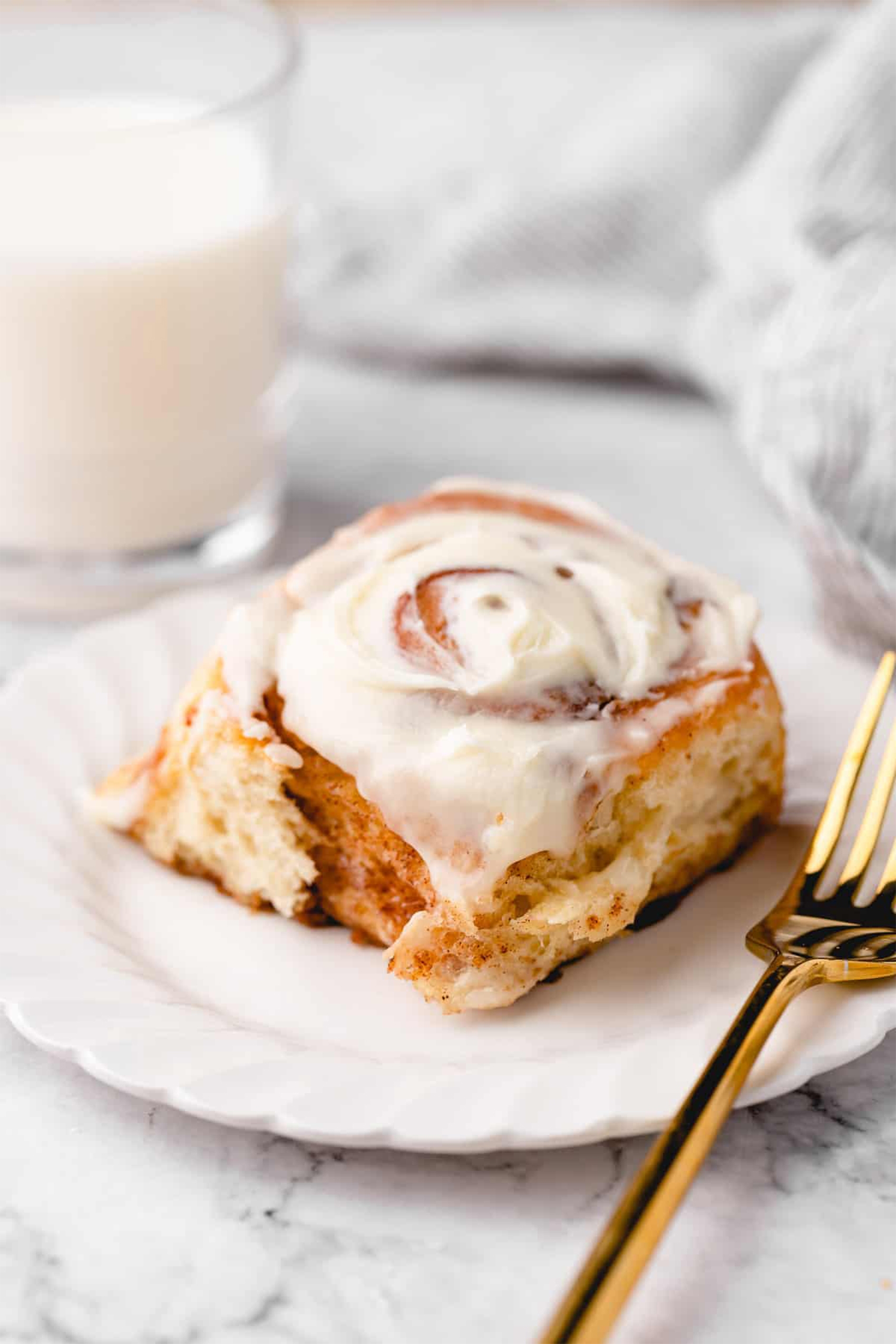 a vegan cinnamon roll topped with frosting