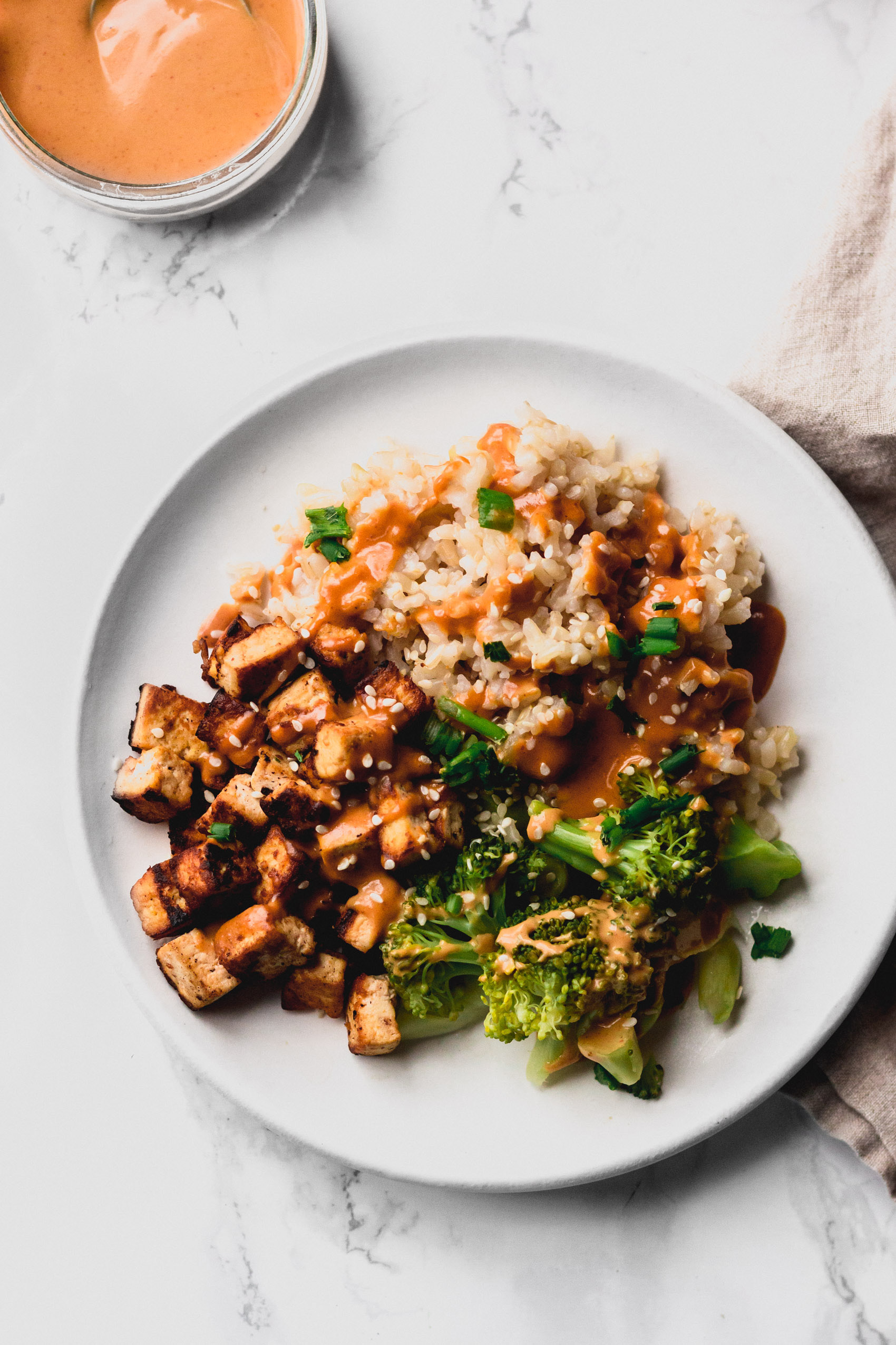 a plate of rice served with tofu, broccoli and a vegan peanut sauce