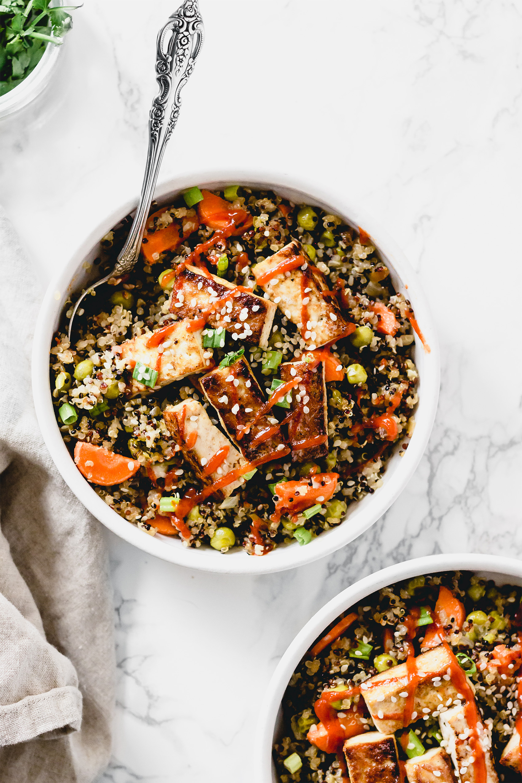 two bowls of quinoa fried rice topped with sriracha