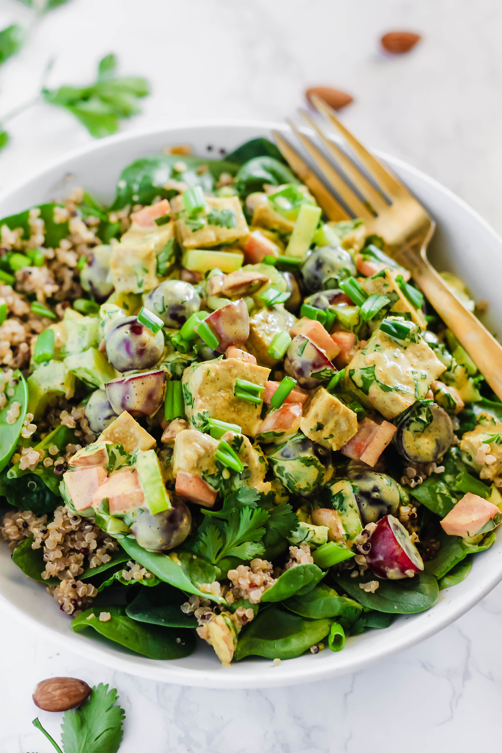 a salad topped with seitan, chopped veggies and herbs