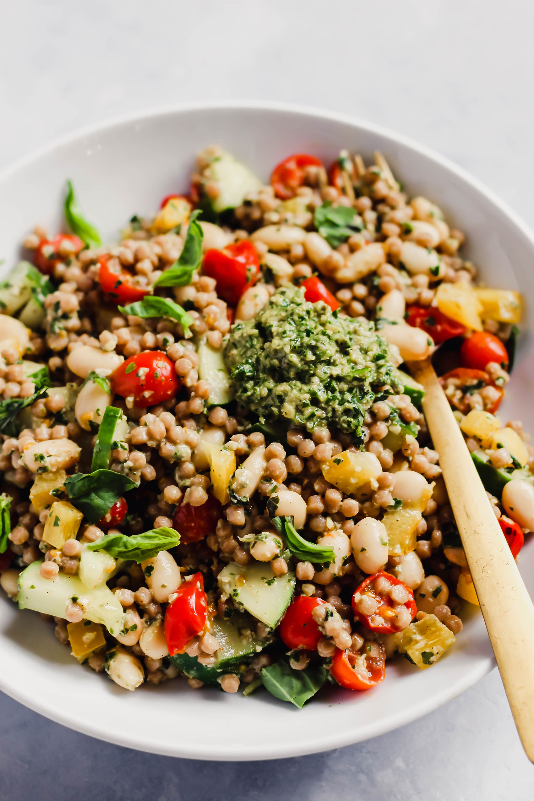 a couscous salad with tomatoes, cucumbers and a pesto dressing