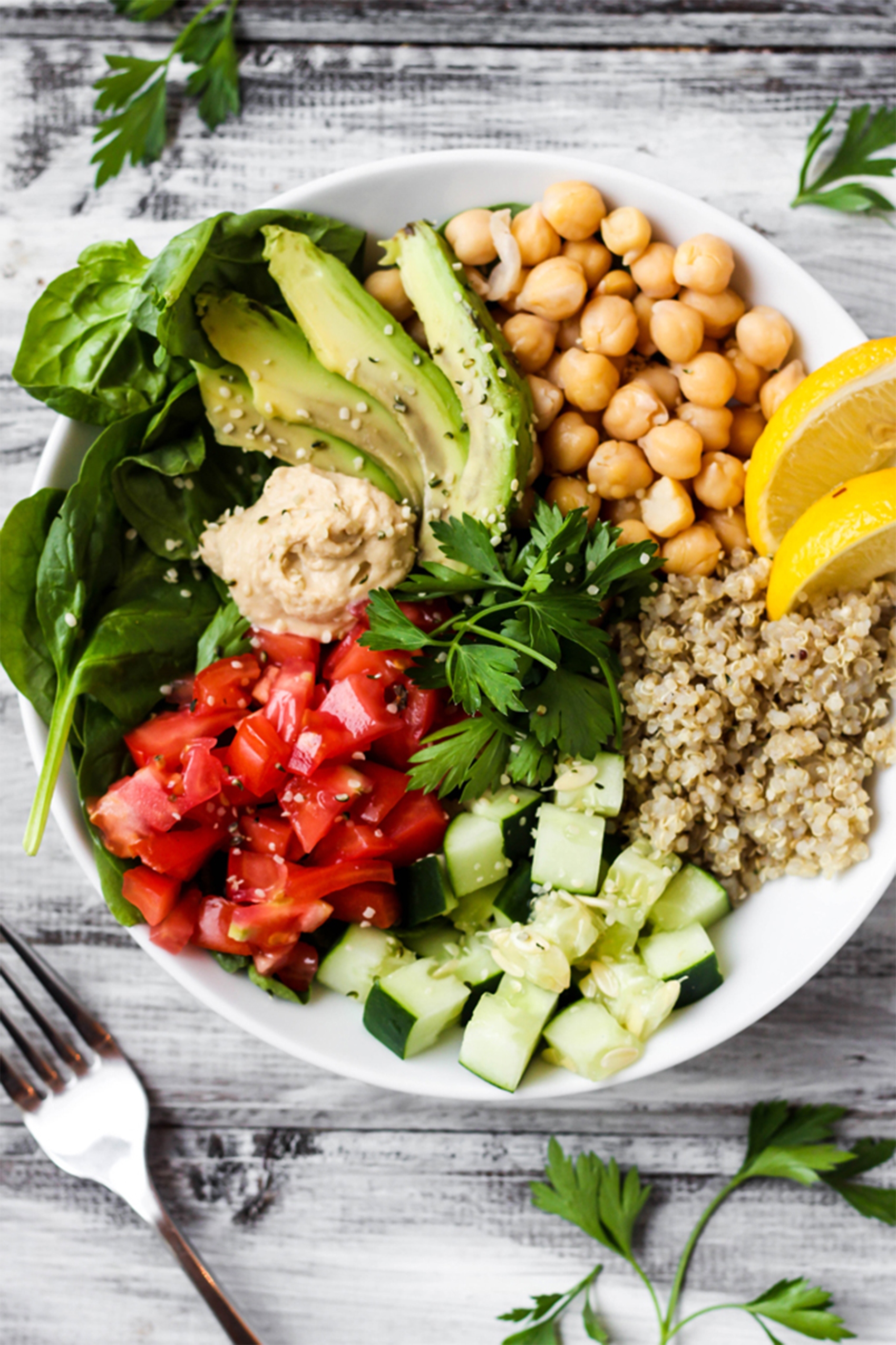 a bowl of tomatoes, cucumber, rice, chickpeas, avocado and greens