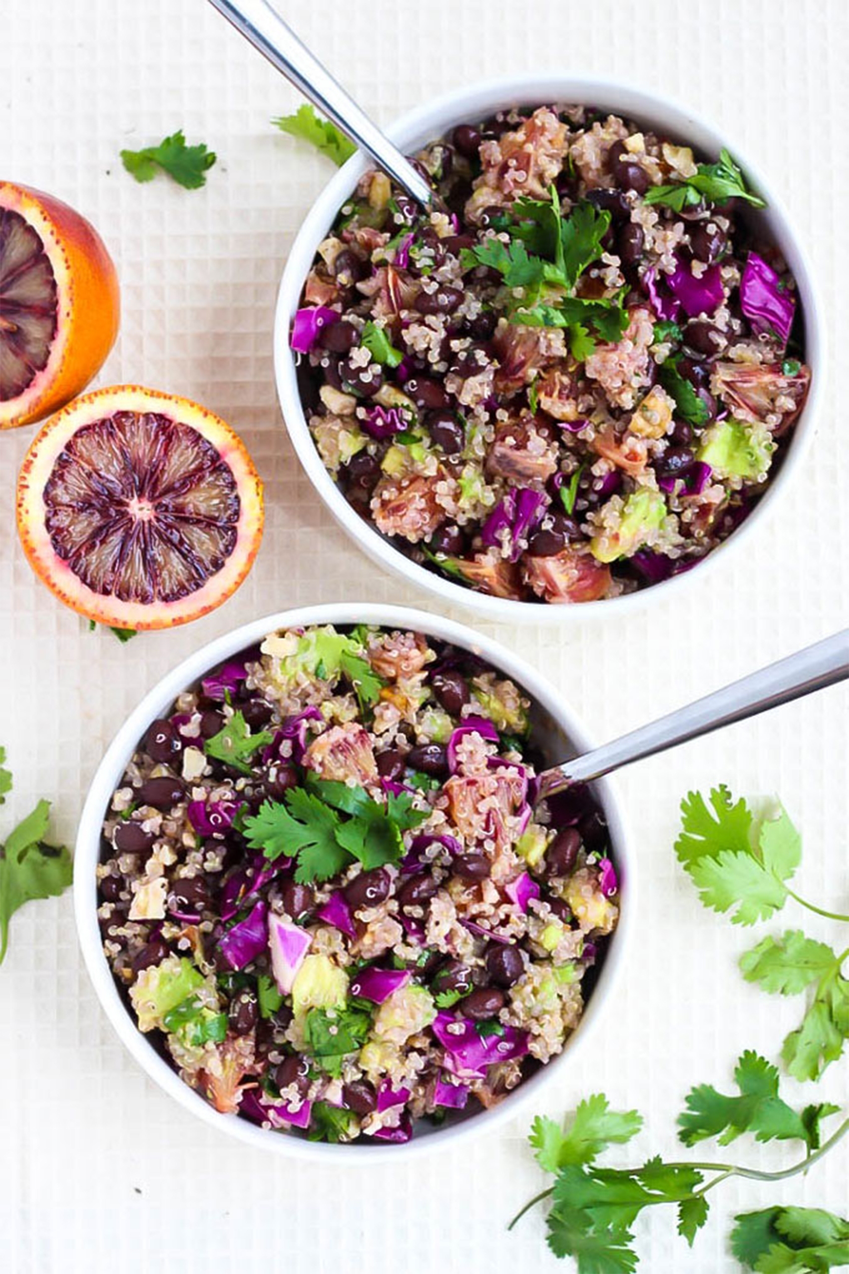 two bowls of blood orange quinoa salad topped with cilantro and avocado