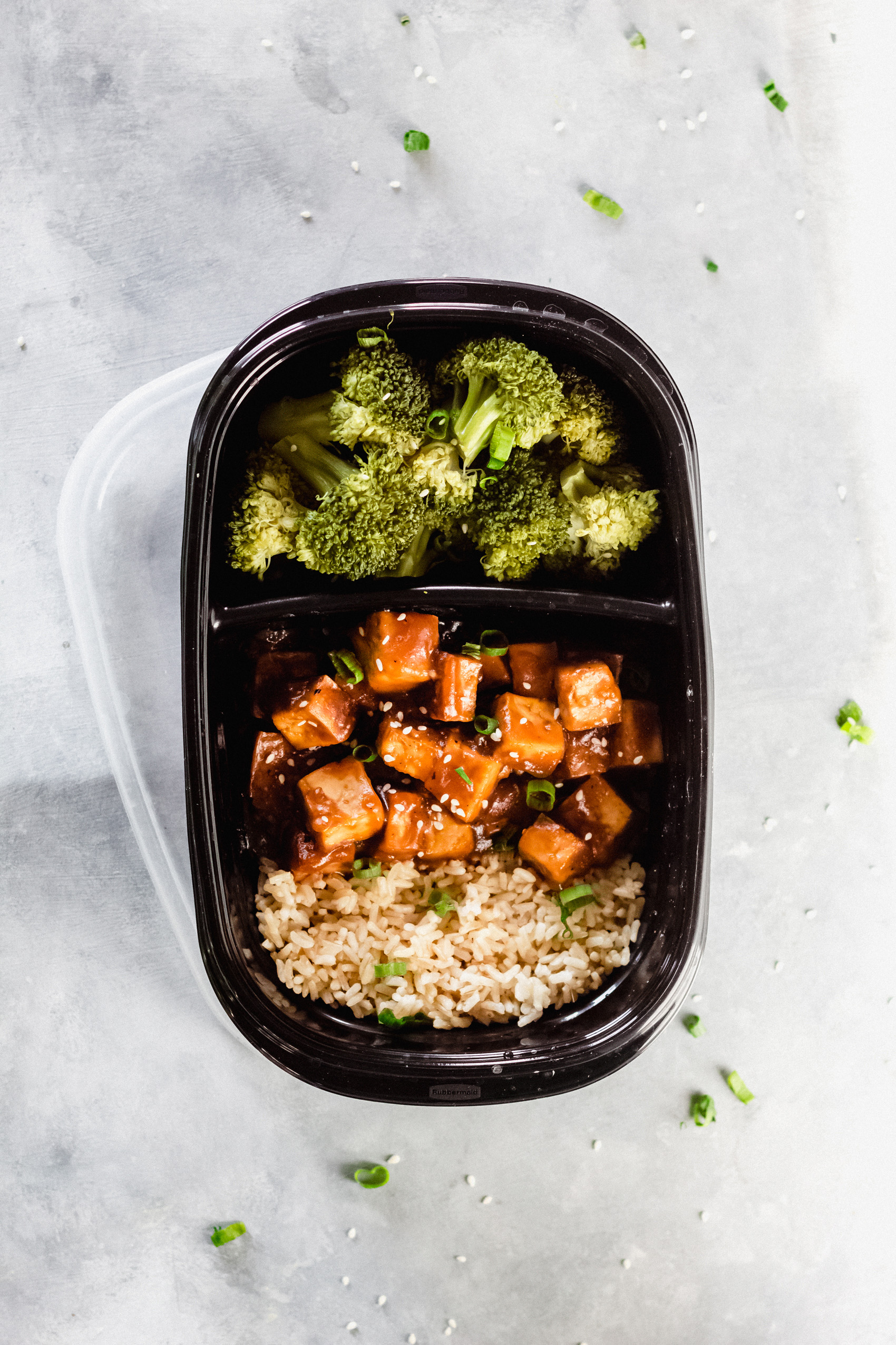 a meal prep container filled with rice, broccoli and teriyaki tofu