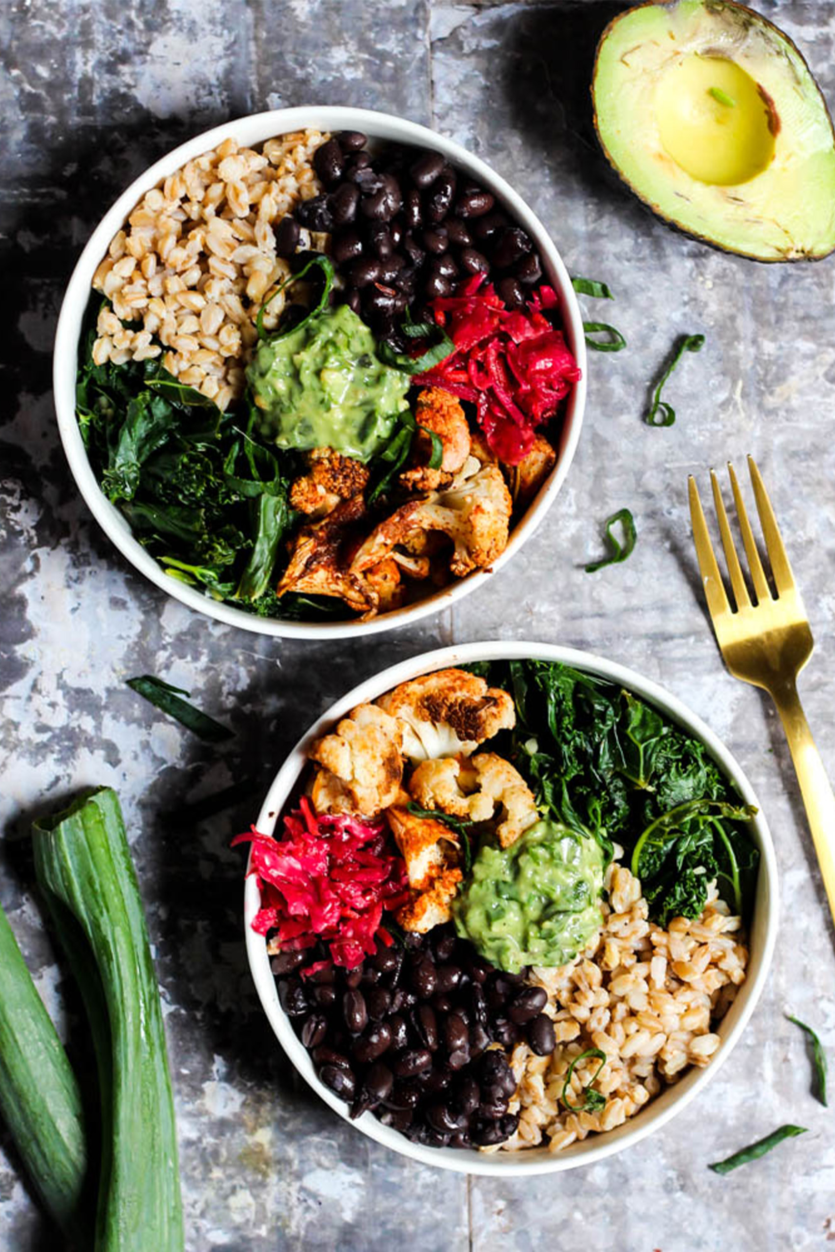 two lunch bowls with rice, black beans, pesto, cauliflower and cabbage