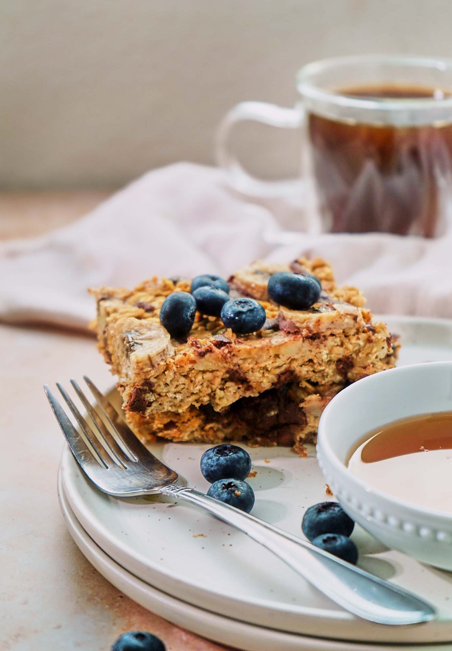 a slice of baked oatmeal served with fresh blueberries and maple syrup