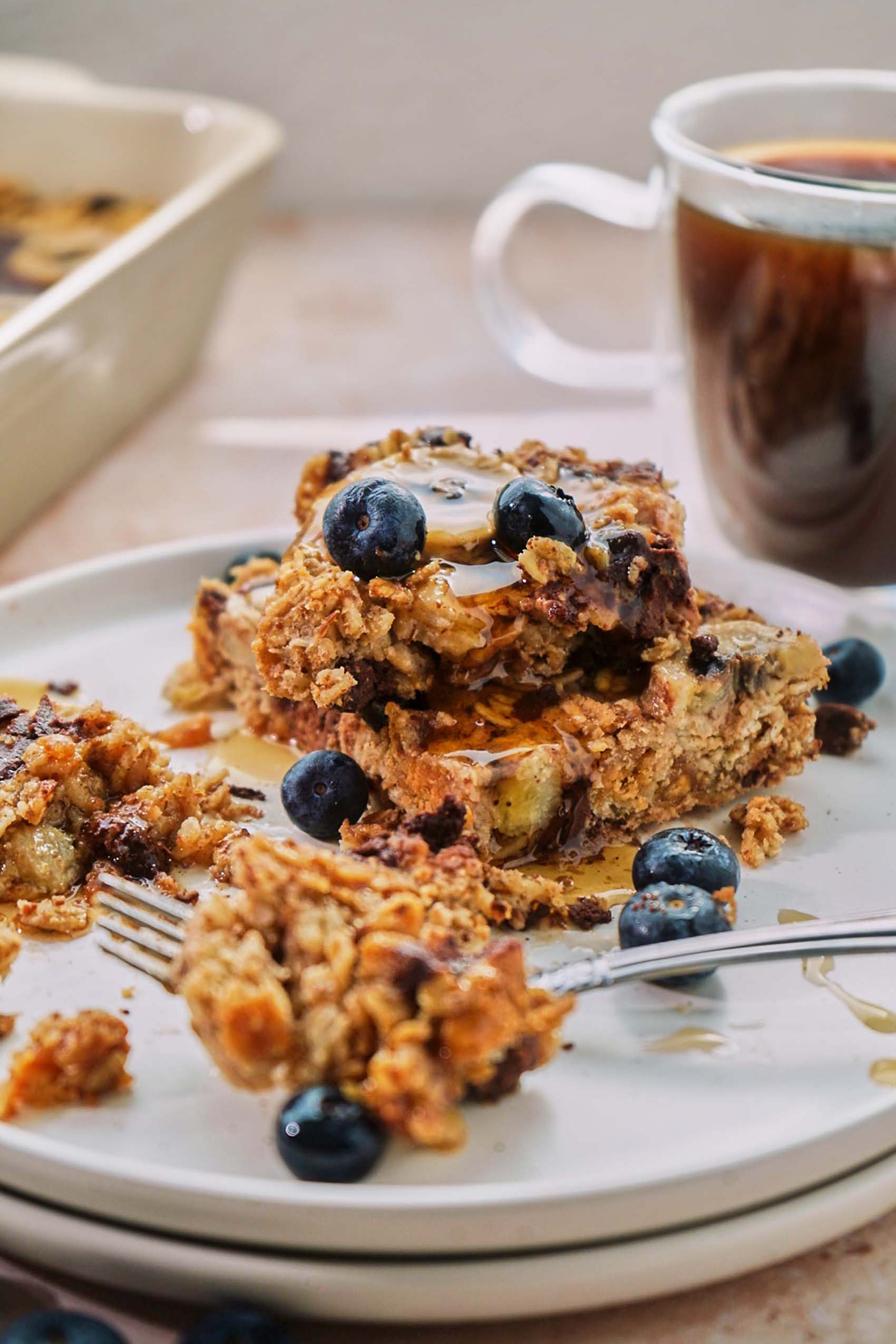 a plate of two sliced of baked oatmeal topped with blueberries