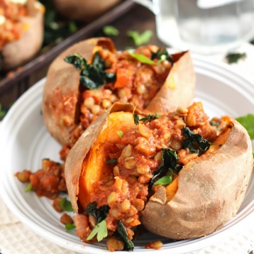 two bbq lentil stuffed sweet potatoes topped with herbs