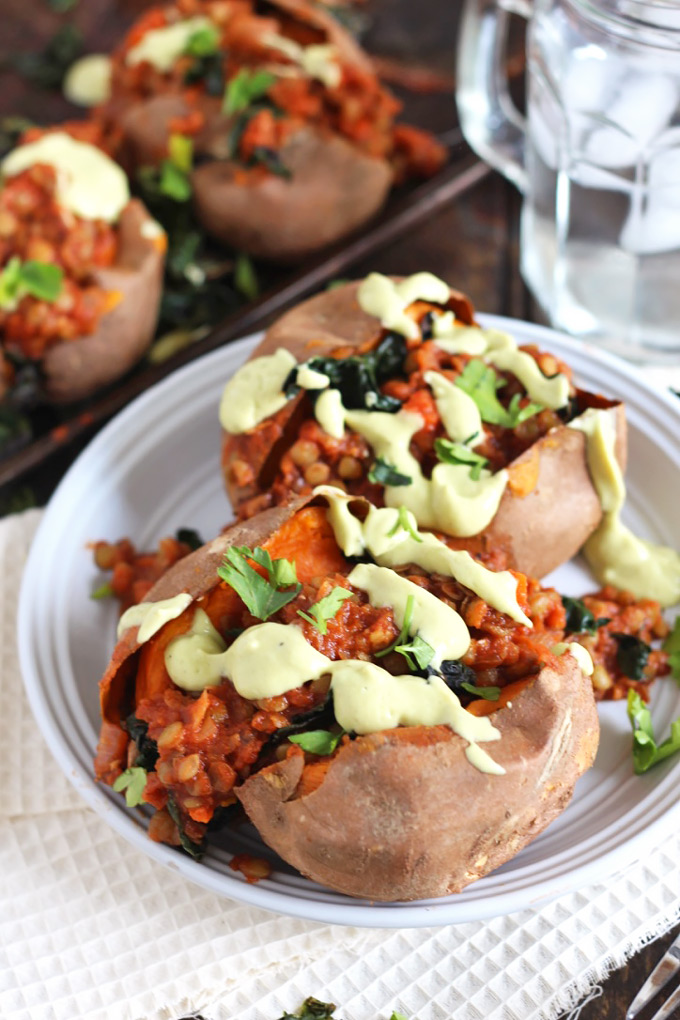 two sweet potatoes stuffed with lentils and topped with an avocado sauce