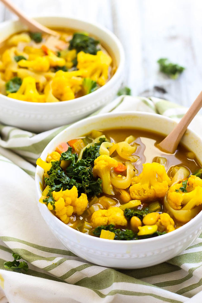 two bowls of vegetable soup featuring cauliflower and kale