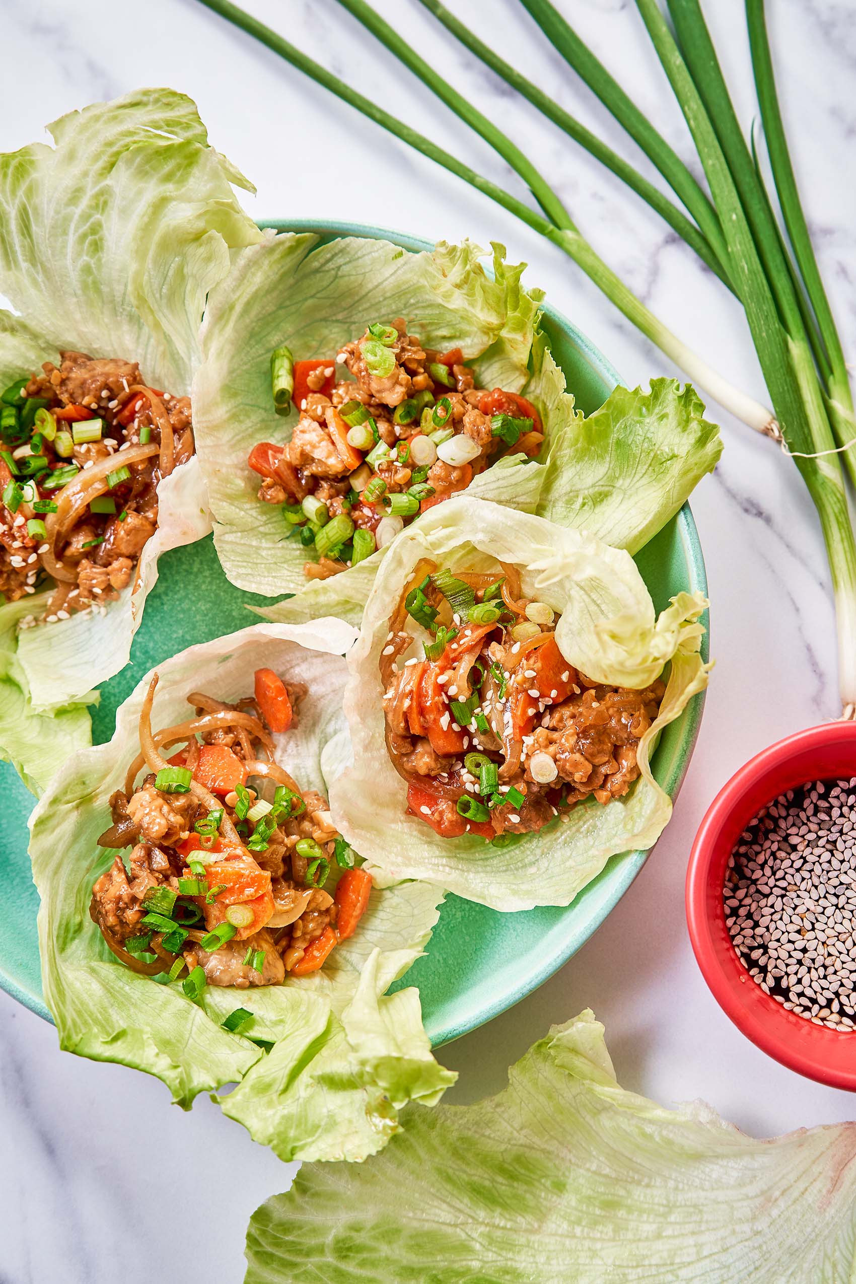 a plate of tempeh lettuce cups served with soy sauce and sesame seeds