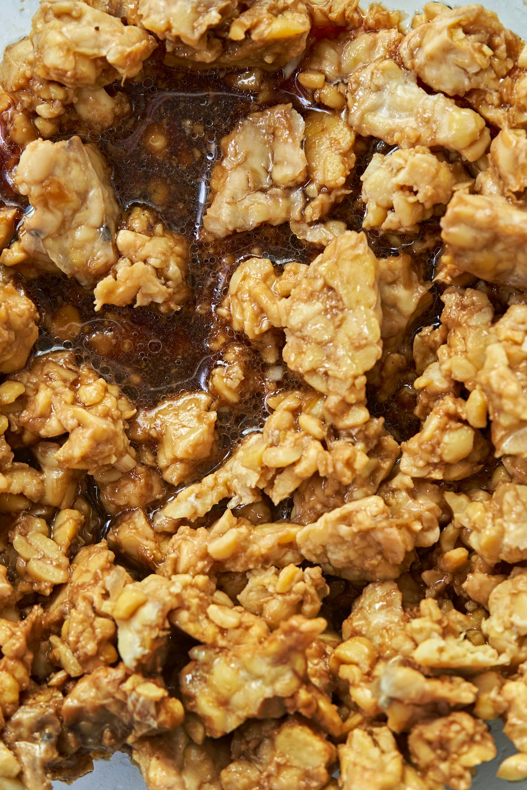 a bowl of tempeh being marinaded in a teriyaki sauce