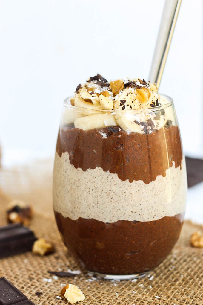 a cup of layered peanut butter and chocolate chia puddings topped with bananas