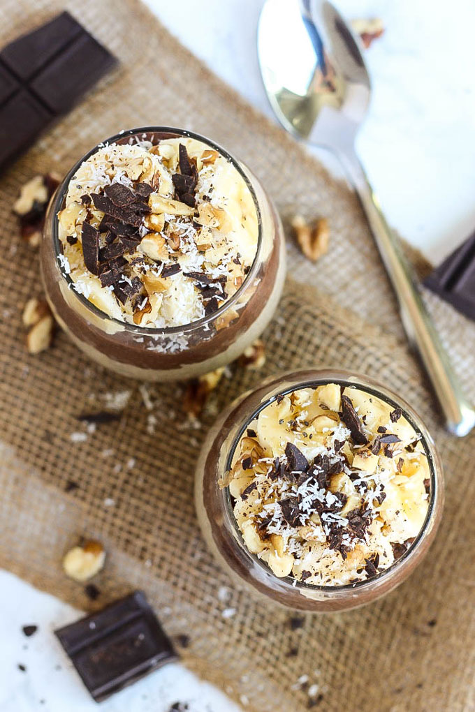 an overhead shot of two cups of chia pudding topped with chocolate and chopped peanuts