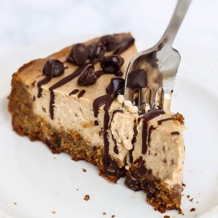a fork digging into the tip of a slice of chocolate chip cheesecake