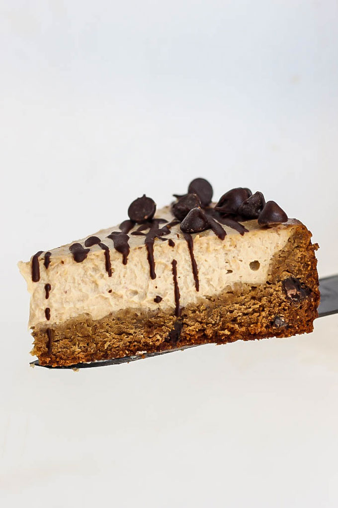 a spatula serving a slice of chocolate chip cookie cheesecake