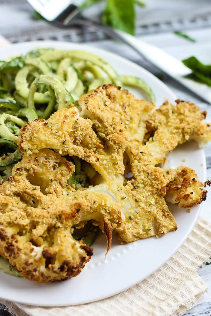 These Vegan Parmesan Cauliflower Steaks over Hemp Pesto Zoodles feel gourmet but are done in 1 hour! This gluten-free dinner is perfect to impress anyone.