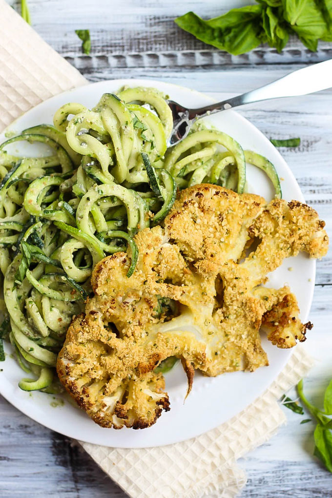 These Vegan Parmesan Cauliflower Steaks over Hemp Pesto Zoodles feel gourmet but are done in 1 hour! This gluten-free dinner is perfect to impress anyone.