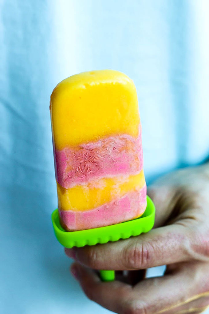 Satisfy your sweet tooth with these healthier Vegan Strawberry Orange Mango Popsicles! Only a few ingredients for a delicious treat that will cool you off.