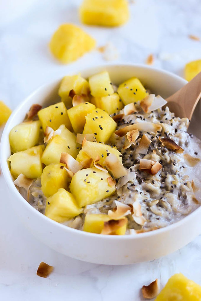 a bowl of coconut oatmeal topped with chia seeds and pineapple
