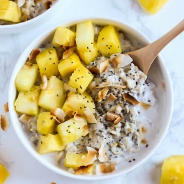a bowl of oats topped with toasted coconut and pineapple