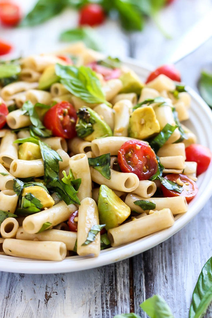 Creamy avocado replaces cheese in this VEGAN Caprese Pasta Salad! Easy to prepare in 30 minutes & full of fresh summer produce. A delicious lunch or dinner!