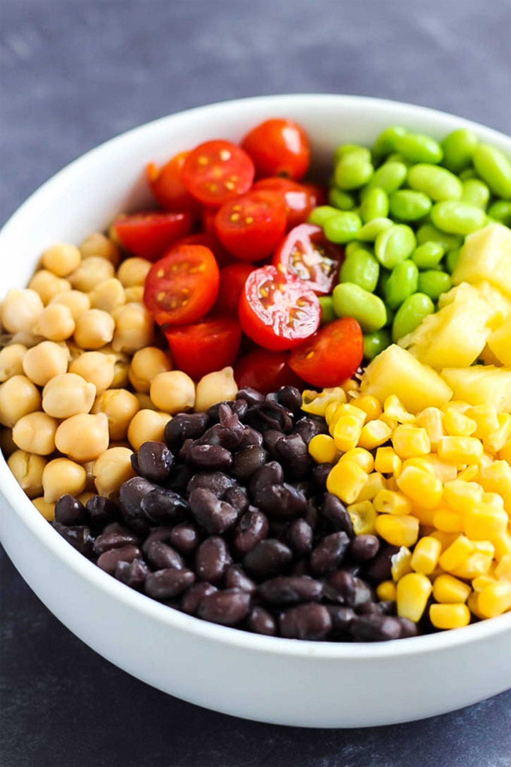 a bowl of black beans, corn, chickpeas, edamame, tomatoes and pineapple