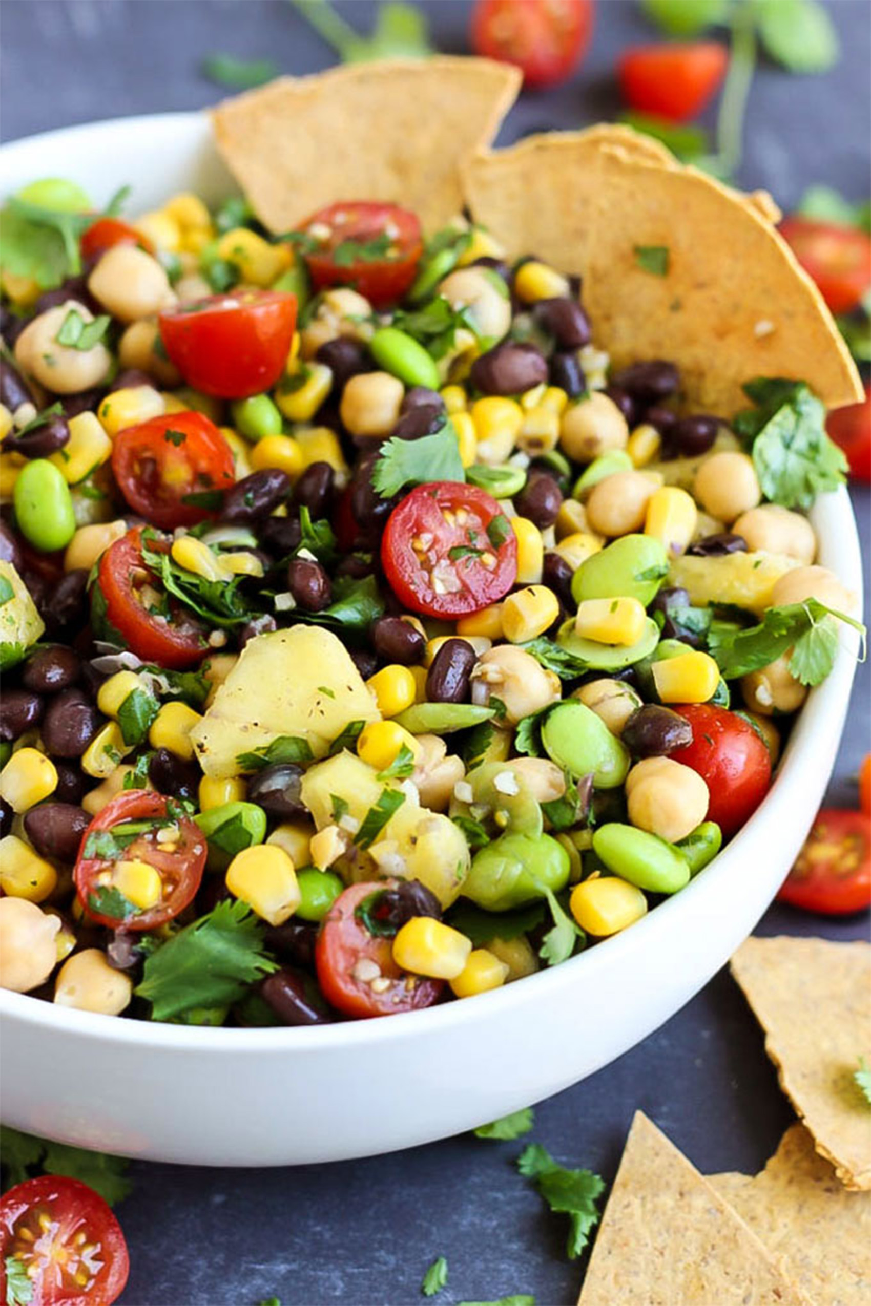 a chip being scooped into a bowl of bean salad