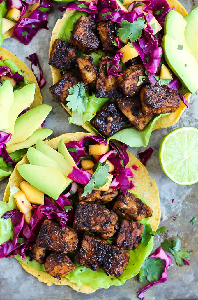 A smoky tempeh tostada topped with mango slaw, cabbage and avocado slices