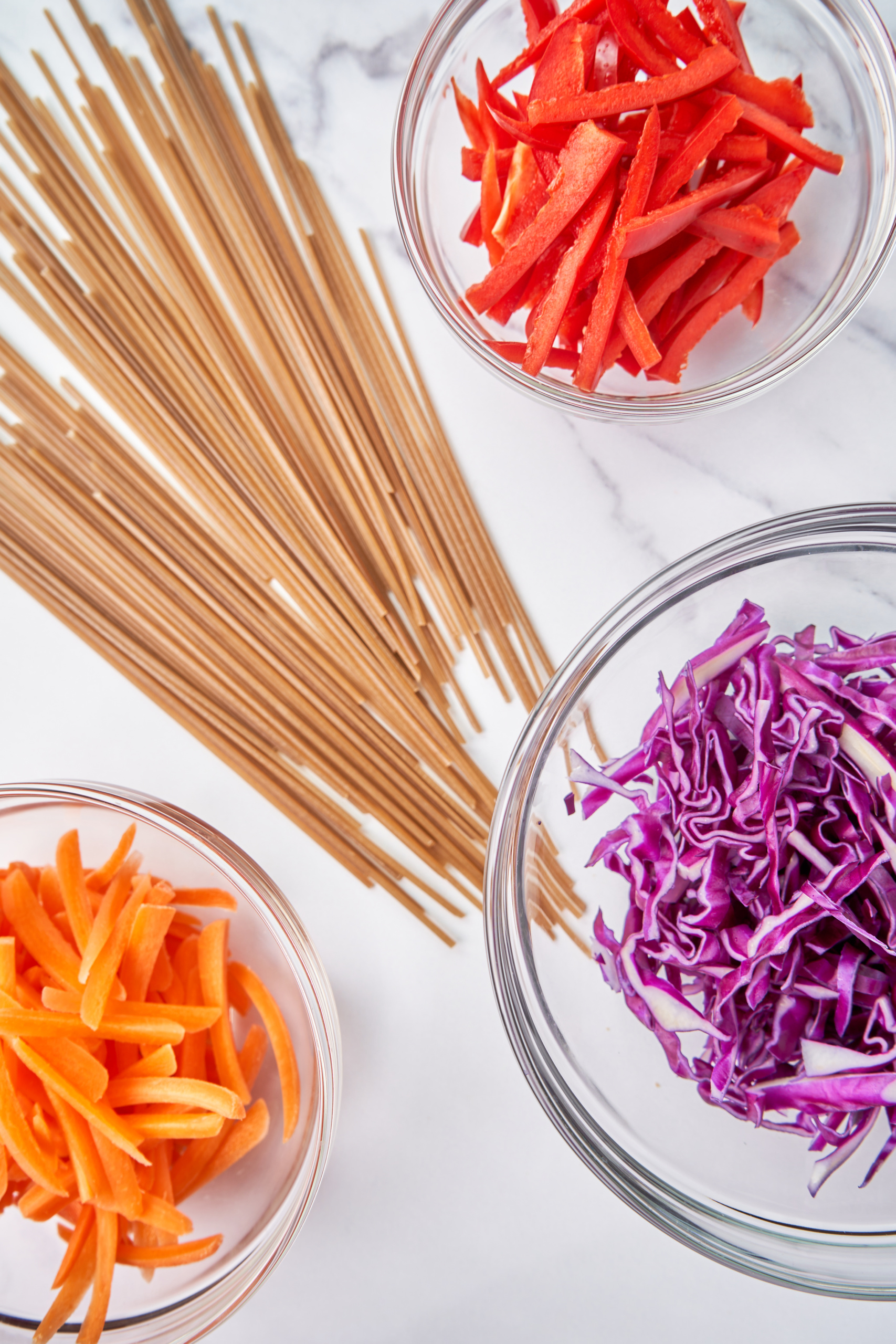 a collection of ingredients being used to make vegetable peanut noodles