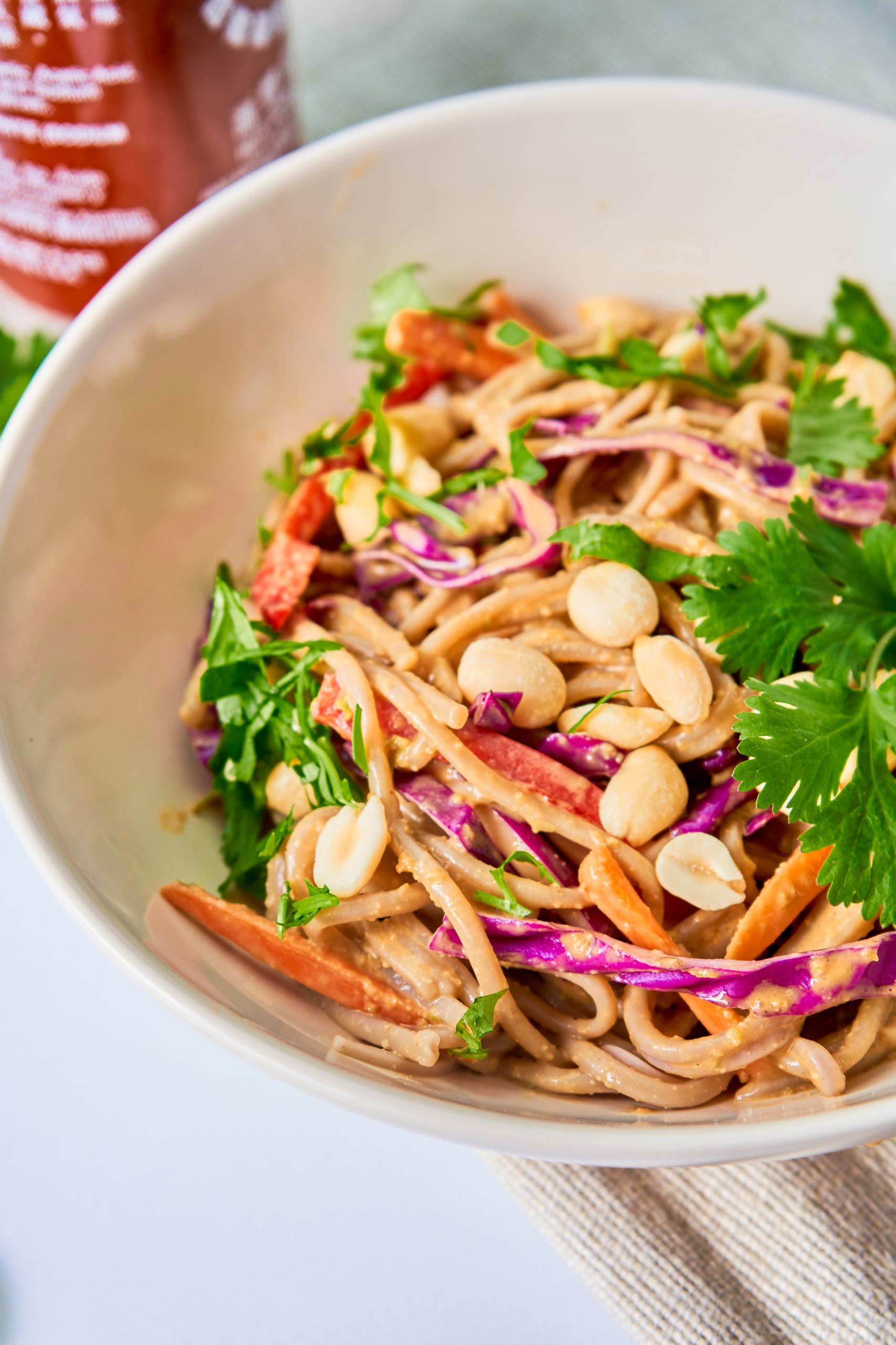 a bowl of peanut soba noodles topped with peanuts and herbs