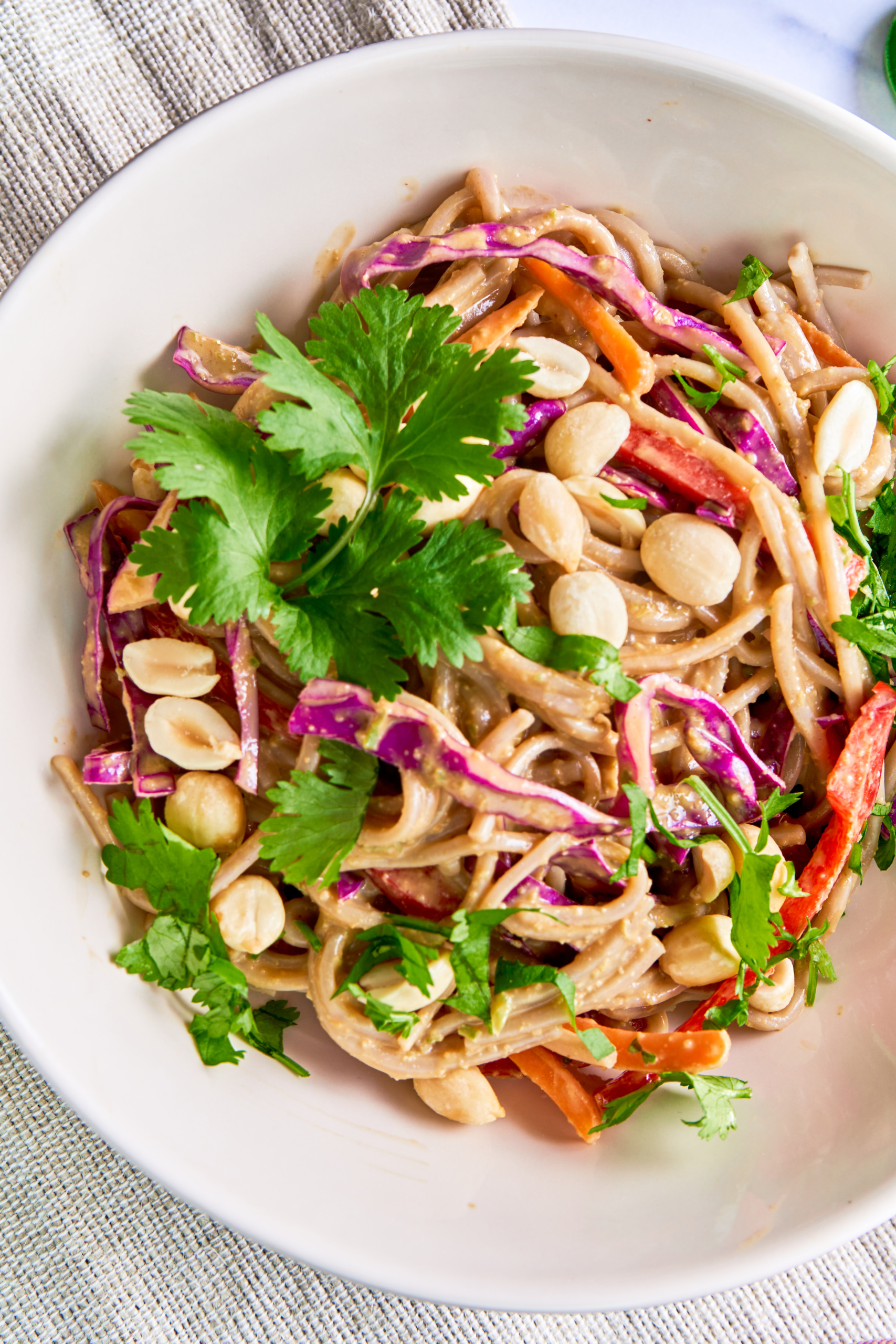 a bowl of vegan soba noodles served with peanuts, cilantro and fresh vegetables