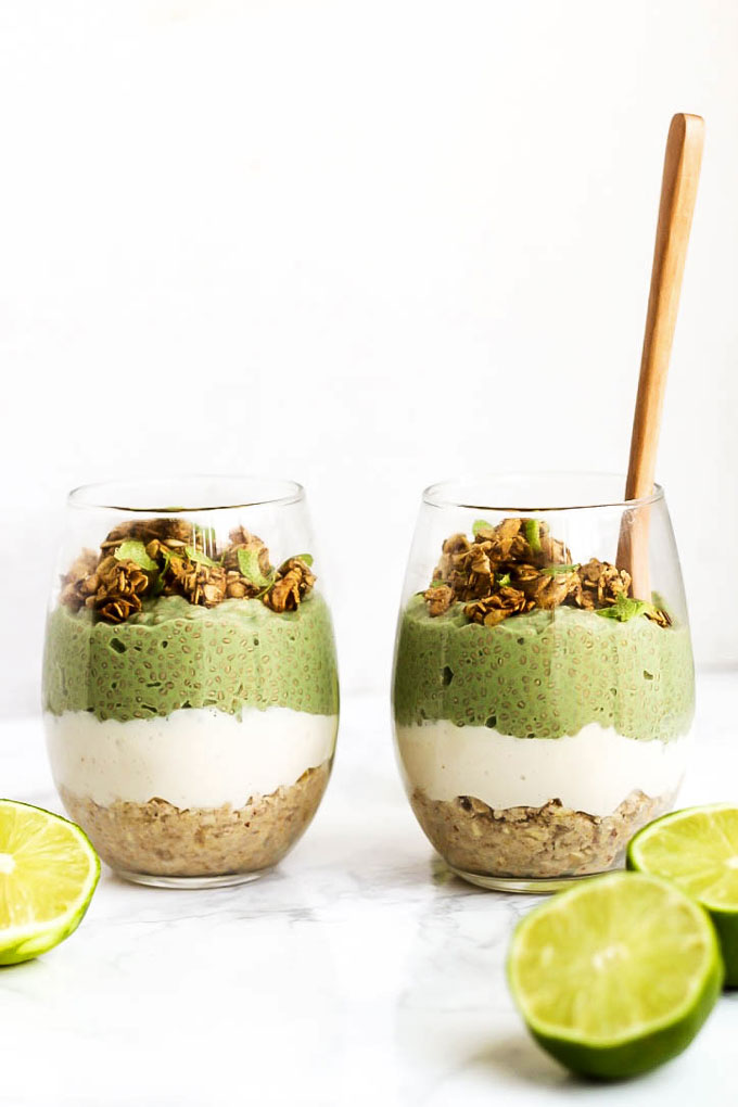 two cups of layered parfaits including an oatmeal crust, vanilla pudding and chia pudding topped with granola
