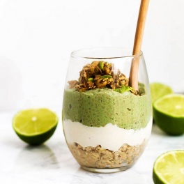 a vegan chia pudding parfait with a layer of oat crust at the bottom, a vanilla pudding in the middle and a green lime-flavored chia pudding on top