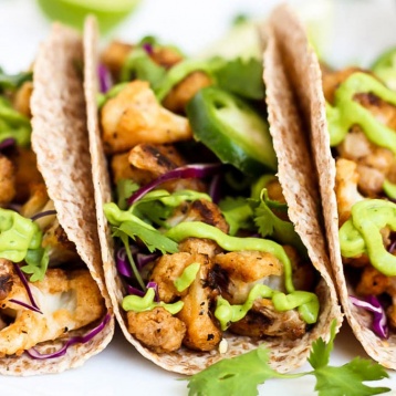 three cauliflower tacos, each topped with jalapenos and avocado sauce