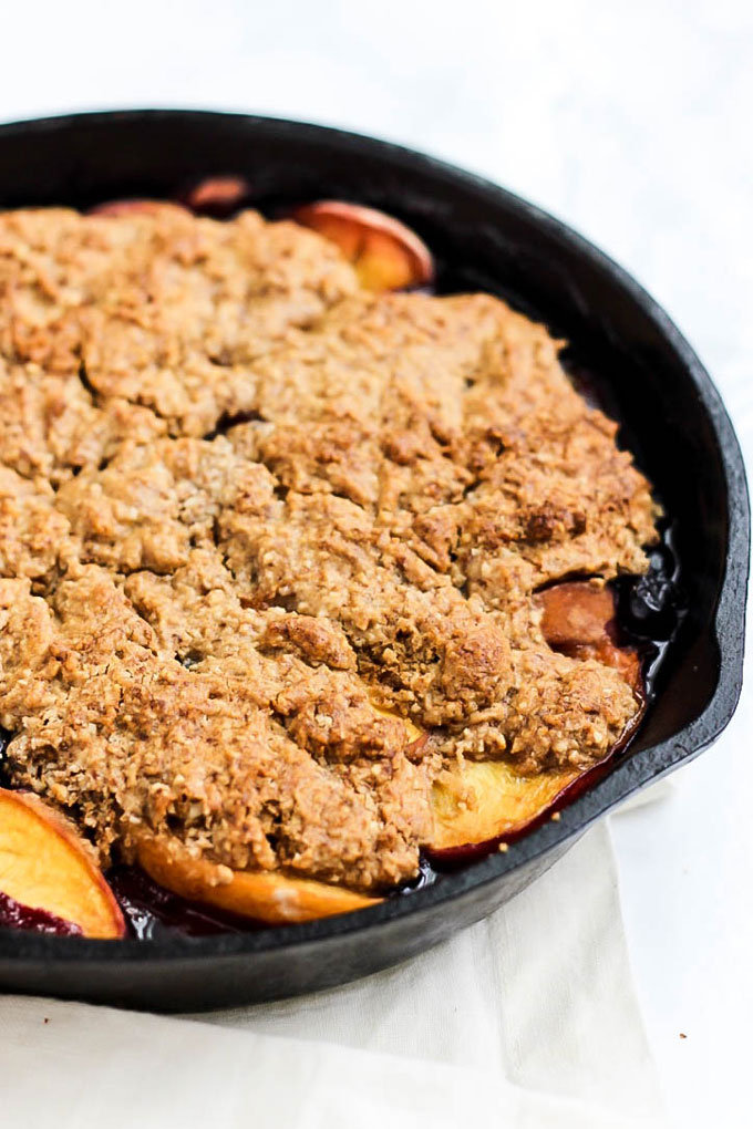 A close up shot of a peach and blueberry cobbler with a gluten-free and vegan topping