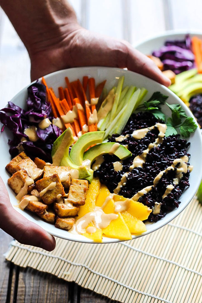 A power bowl packed with vegetables, sriracha tofu, black rice and a tahini drizzle