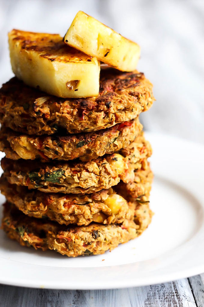 A stack of chickpea veggie burgers topped with two wedges of grilled pineapple