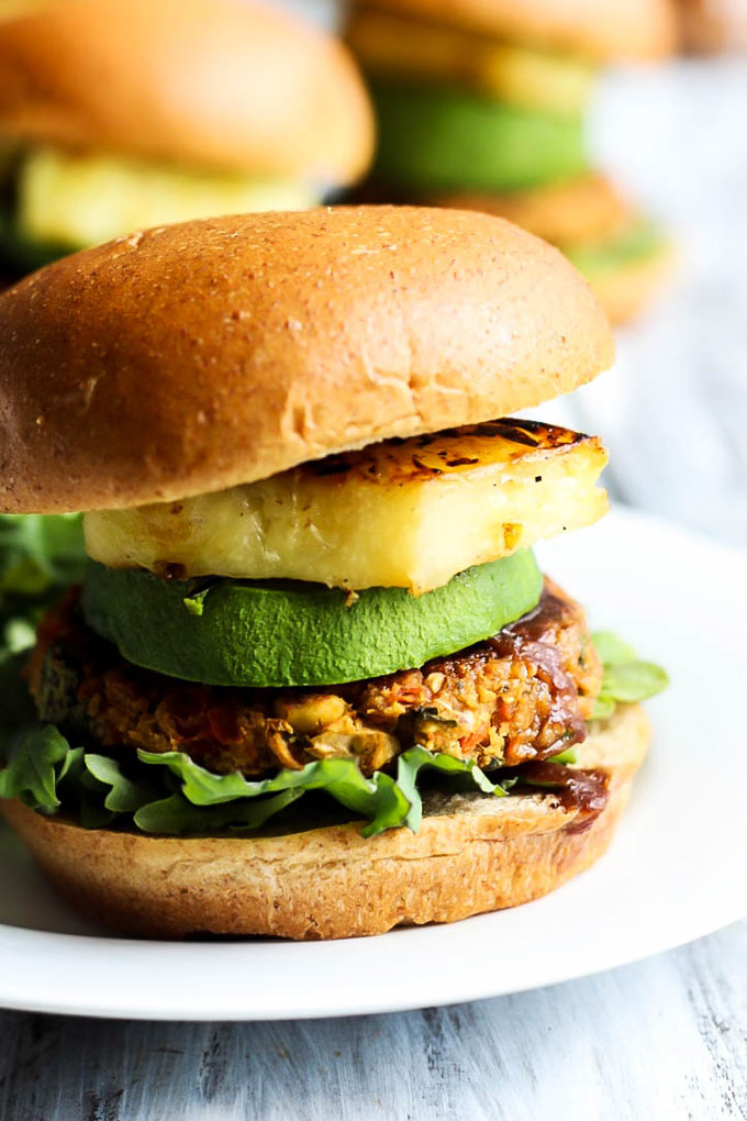 A vegan chickpea patty served on a bun with lettuce, bbq sauce, avocado and grilled pineapple