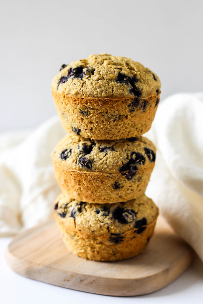 three blueberry cornmeal muffins stacked on top of one another