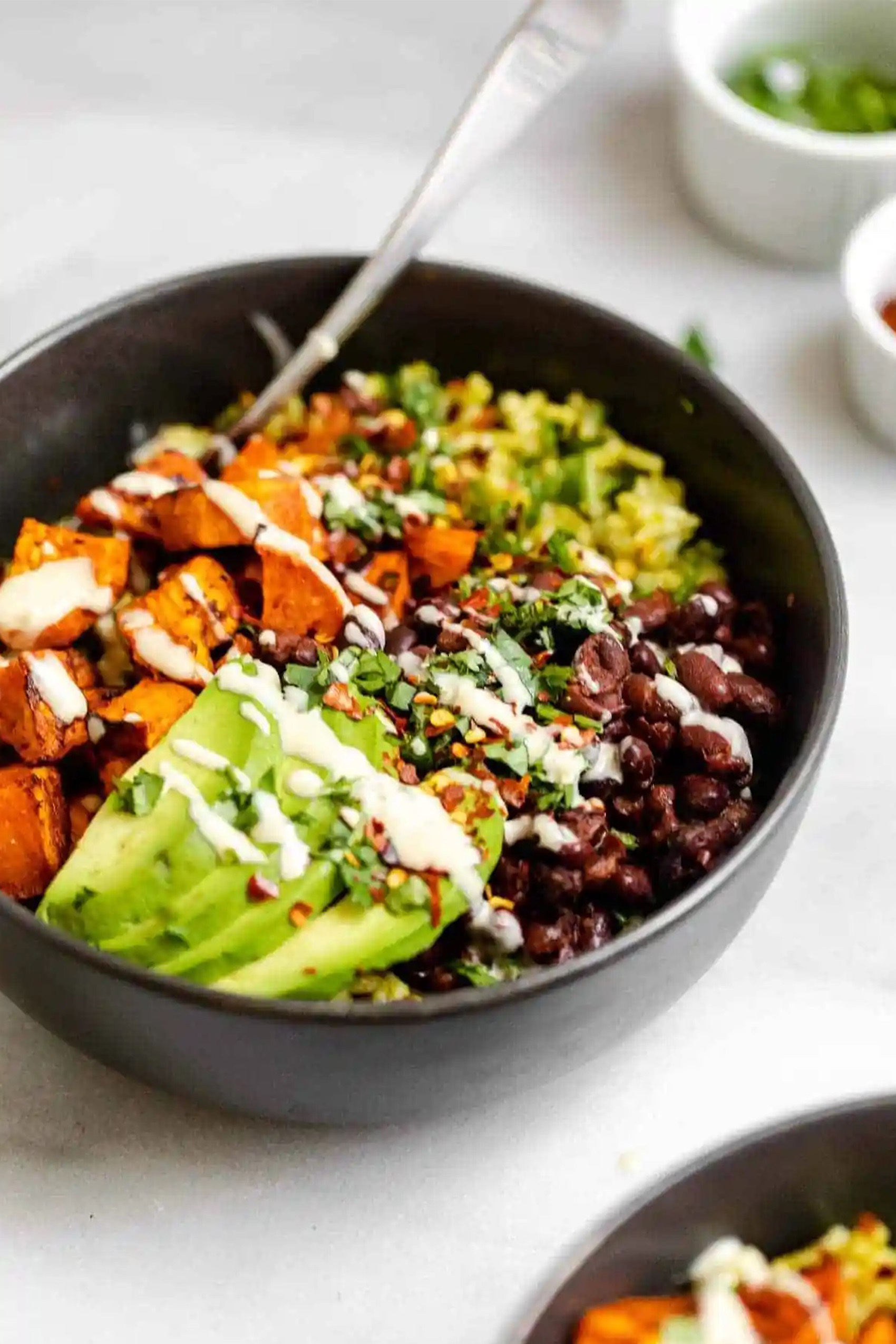 a vegan power bowl with rice, olives, avocado and sweet potatoes