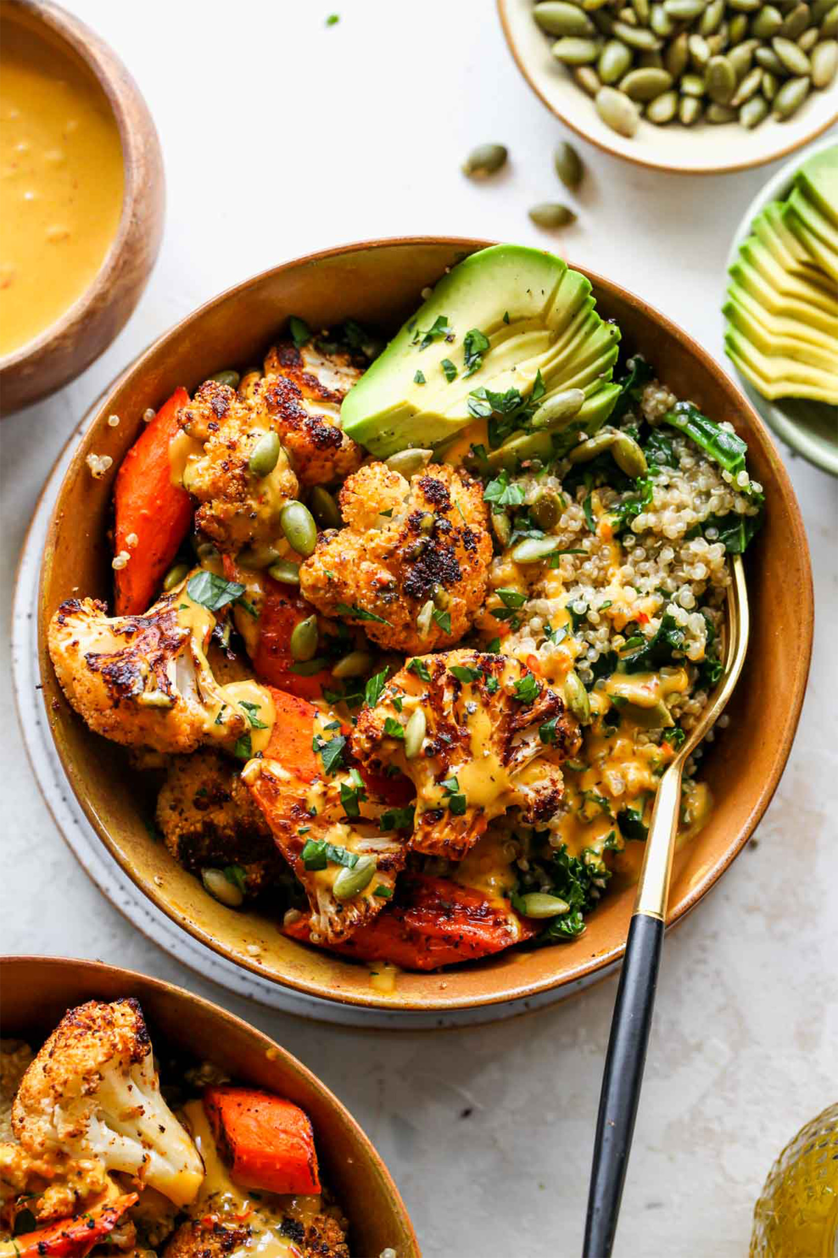 a vegan cauliflower bowl with quinoa, avocado and cooked veggies